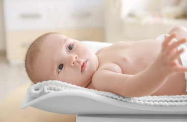 Cute little baby lying on scales at home