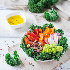 Healthy vegan buddha bowl with kale leaves and raw vegetables