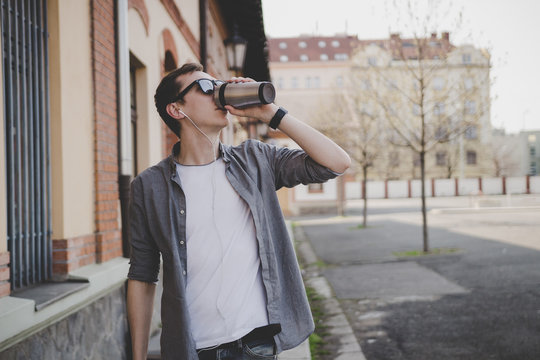 Young hipster man walking on the street and drinking coffee