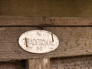 a metal sign stapled to a fence saying traditional oval shining retro vintage wooden background
