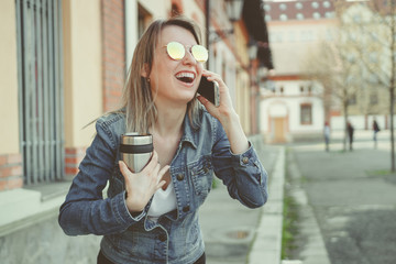 Fototapeta premium Beautiful blonde young woman walking on the street, talking on phone