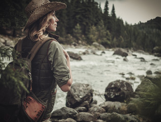 Beautiful woman hiker near wild mountain river.