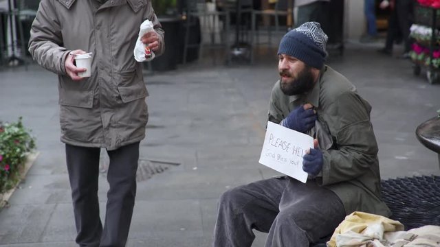 Sweet old man offers breakfast to a solitary beggar in the street