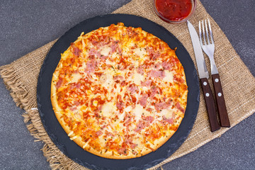 Pizza with ham and cheese on black stone