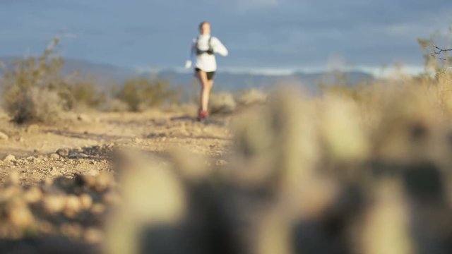panning shot of girl trail running in desert