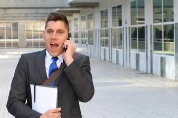 Surprised businessman getting great news on the phone