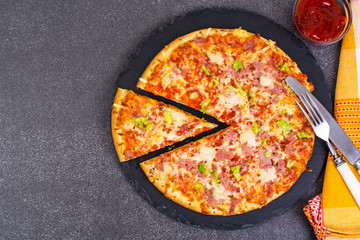 Pizza with ham and cheese on black stone