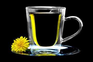 Dandelion tea in the transparent cup on black background