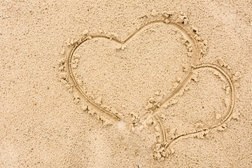  Two hearts painted enamored on the sand near the river background
