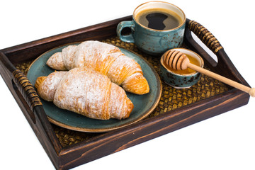 Croissant, honey and espresso in blue vintage bowl on wooden tra