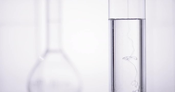 Translucent gel is dropped into test tube with liquid