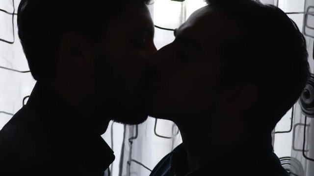 Silhouette of gay men kissing tenderly