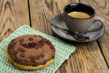 One donut in chocolate glaze on wooden background