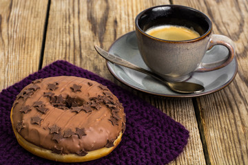 One donut in chocolate glaze on wooden background