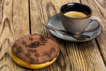 One donut in chocolate glaze on wooden background