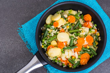Frying pan with fried vegetables on blue napkin