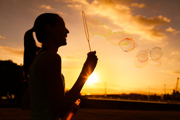 Silhouette of girl having fun blowing bubbles. 
