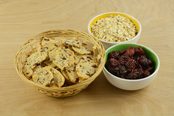 Cranberry oat crispbread snacks in wooden basket with bowls of dried cranberries and oats