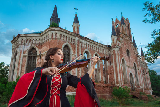 Musician playing the violin near an old castle