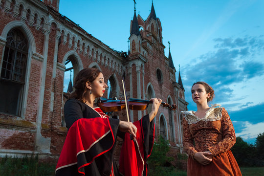 Violinist playing the violin for a woman dressed in the style of the Shakespeare era