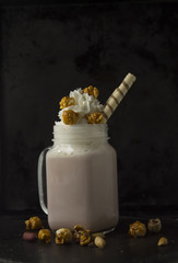 Milk cocktail on a black background with popcorn and walnuts