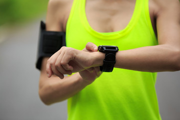 Young fitness woman runner set the sports watch before running