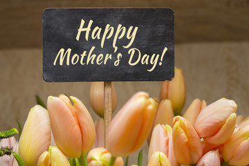 Postcard with cream tulips and sign Happy Mother's Day on the plaque. Bouquet of colorful flowers