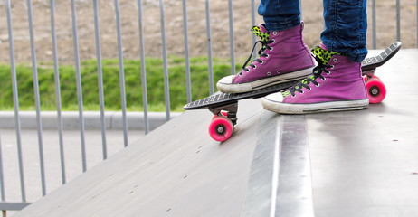 Closeup on girl's feet standing on the skateboard before jumping on the railing in a skating park © kyrychukvitaliy