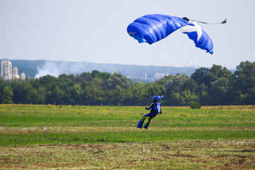 The skydiver landing on grass airfield.