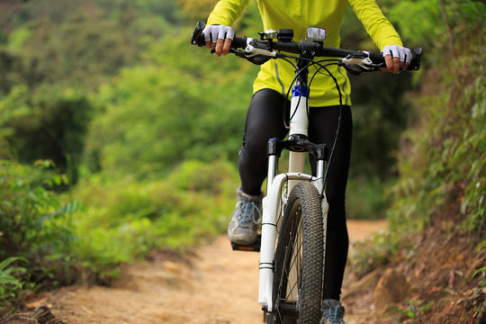 Young woman cyclist cycling mountain bike on forest trail