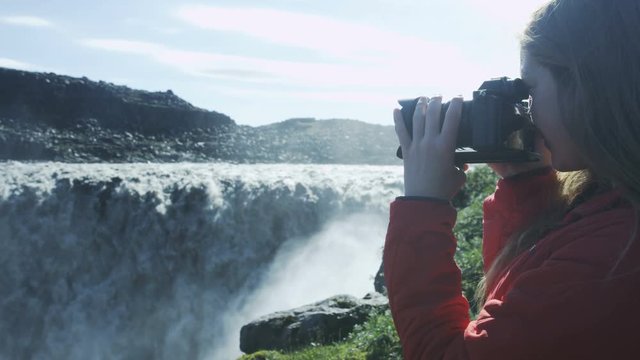 woman taking photograph of waterfall