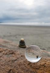 Fototapeta na wymiar Stein Stapel am Strand mit Glaskugel Senkrecht