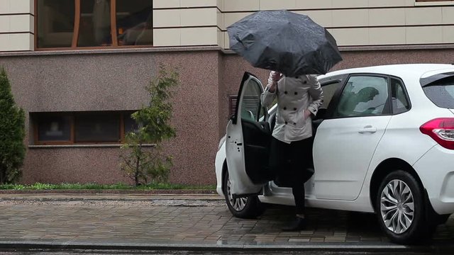 The young guy gets out of the car and immediately opens the umbrella