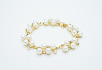 on a white background lies a pearl necklace on the neck and bracelet 