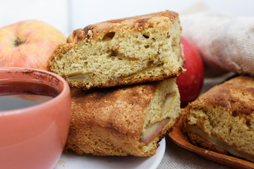 Apple pie charlotte, ripe apples and a cup of coffee on the table