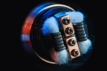 Close-up of cotton wool, coil and electronic cigarette vape on a black wood background. vaping...