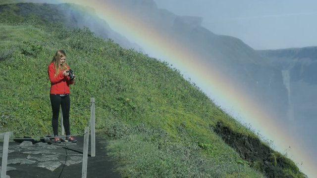 woman taking photos with rainbow in background