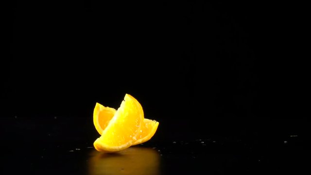 falling orange fruit slices on black, slow motion