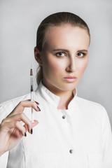 Female doctor or scientist in medical gown with syringe on white background