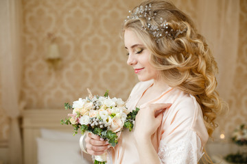 Pretty young Bride. Blonde woman with luxurious long curly hair. Boudoir morning of the bride. Taking wedding bouquet in her hands