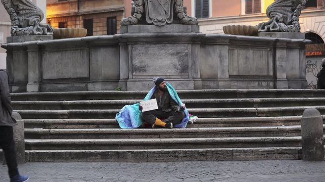 homeless sitting on the stairs asking charity, young man give him money