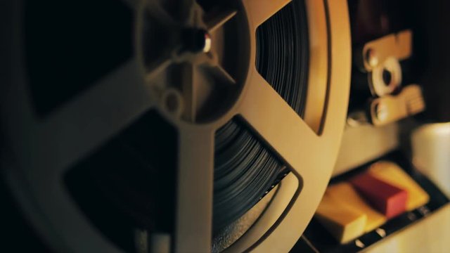 Old 8mm film projector playing in the night. Close-up of a reel with a film. 4k