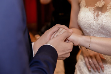 Obraz na płótnie Canvas Bride and groom holding hands during wedding ceremony