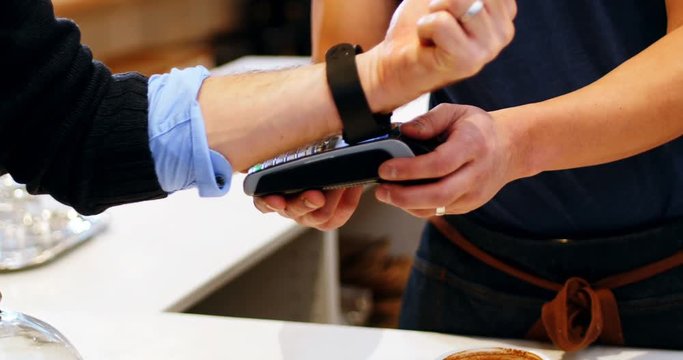 Hand of customer making payment through smartwatch