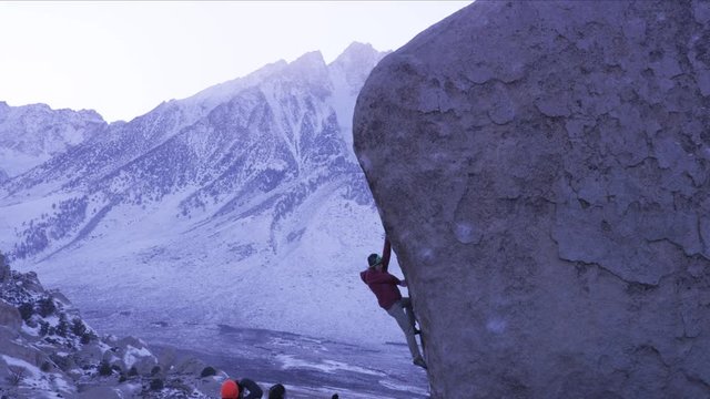 man climbing on boulder with group of climbers below