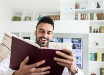 Fototapeta premium Young confident man reading book at modern home