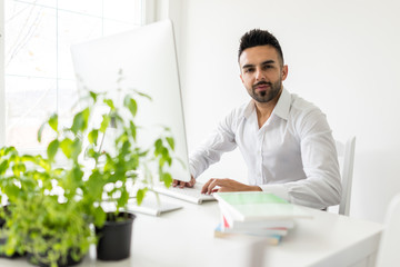 Young confident man working in modern office full of light