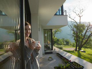 woman drinking coffee in front of her luxury home villa