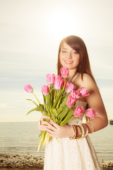 Portrait of woman holding pink flowers on beach