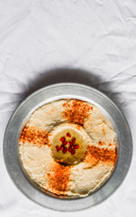 Hummus with paprika, olive oil, and pomegranate seeds against white background. Selective focus.